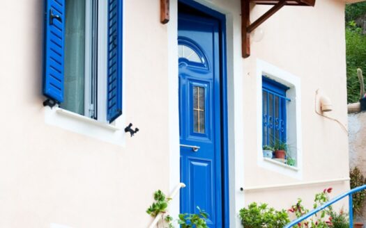 Traditional Greek house with blue shutters representing best real estate deals and property buying in Greece.