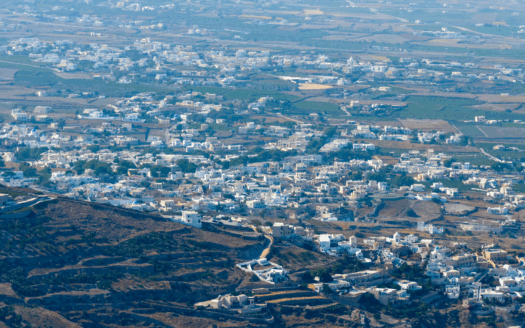 Aerial view of Santorini, Greece, showcasing its iconic white buildings and blue-domed churches, highlighting the impact of tourism on local real estate.