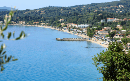 Ipsos Beach in Corfu with crystal-clear blue waters and sun loungers"