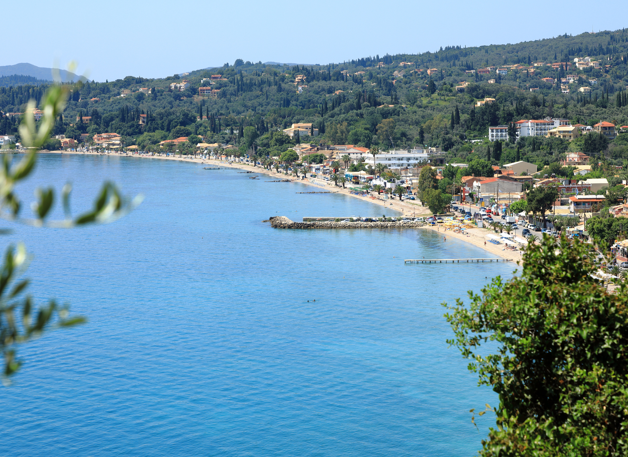 Ipsos Beach in Corfu with crystal-clear blue waters and sun loungers"