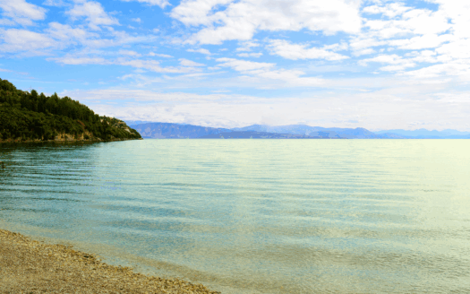 Ipsos Beach in Corfu with clear blue water and sunbathers relaxing.